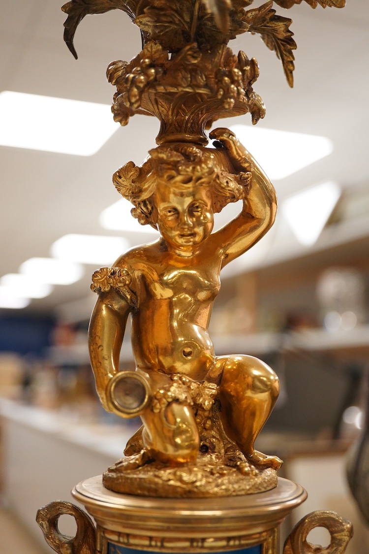A pair of 19th century brass four light figural candelabra with inset enamel plaques, 48cm high